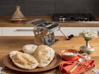 Marcato Atlasmotor 110V attached to silver Atlas 150 roller making perfect lasagna sheets on wooden counter