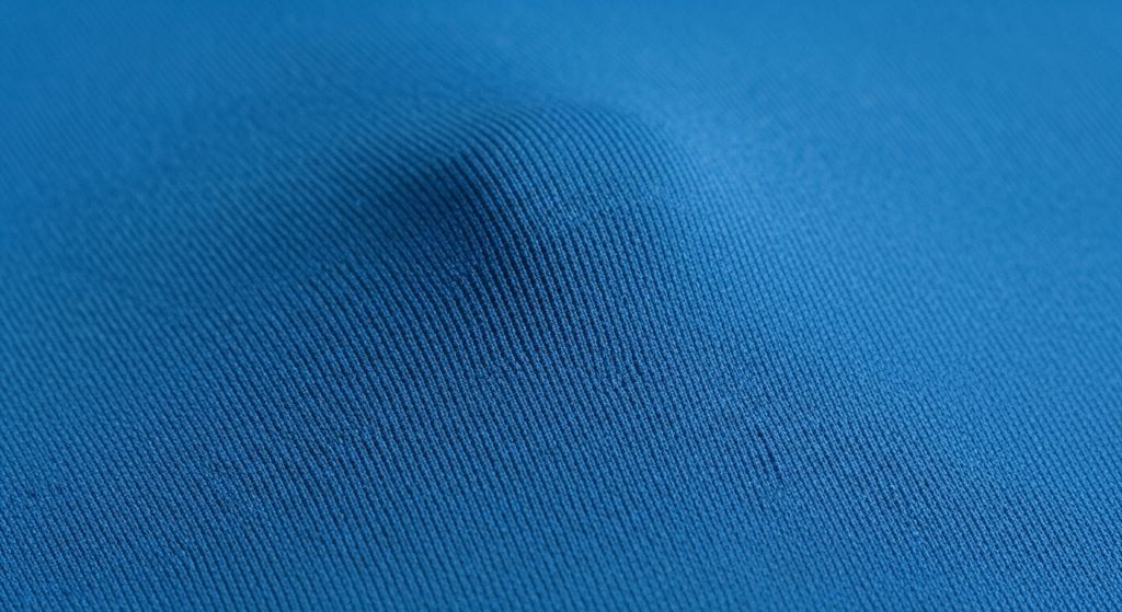 Close-up of athletic compression rash guard fabric showing tight weave and four-way stretch technology for surf performance
