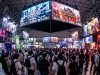 Thousands of visitors exploring colorful game booths inside the crowded exhibition halls of Makuhari Messe during Tokyo Game Show 2026, with large promotional screens displaying upcoming game titles