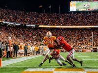 College football players competing in the first round of the 2026–27 College Football Playoff at a packed on-campus stadium under the lights in December 2026