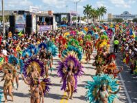 Thousands of costumed masqueraders in feathered and sequined costumes dancing along the Parade of Bands route at Miami Broward Carnival 2026 at the Miami-Dade County Fairgrounds